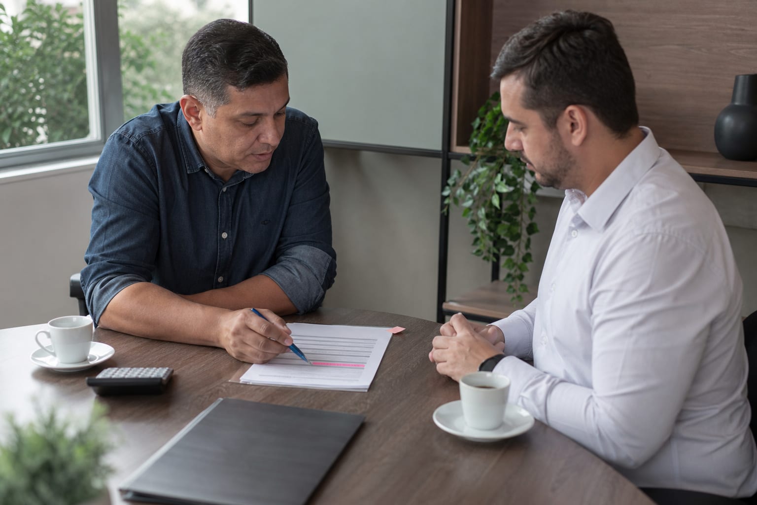 Contador e empresário analisam uma proposta impressa durante reunião em escritório